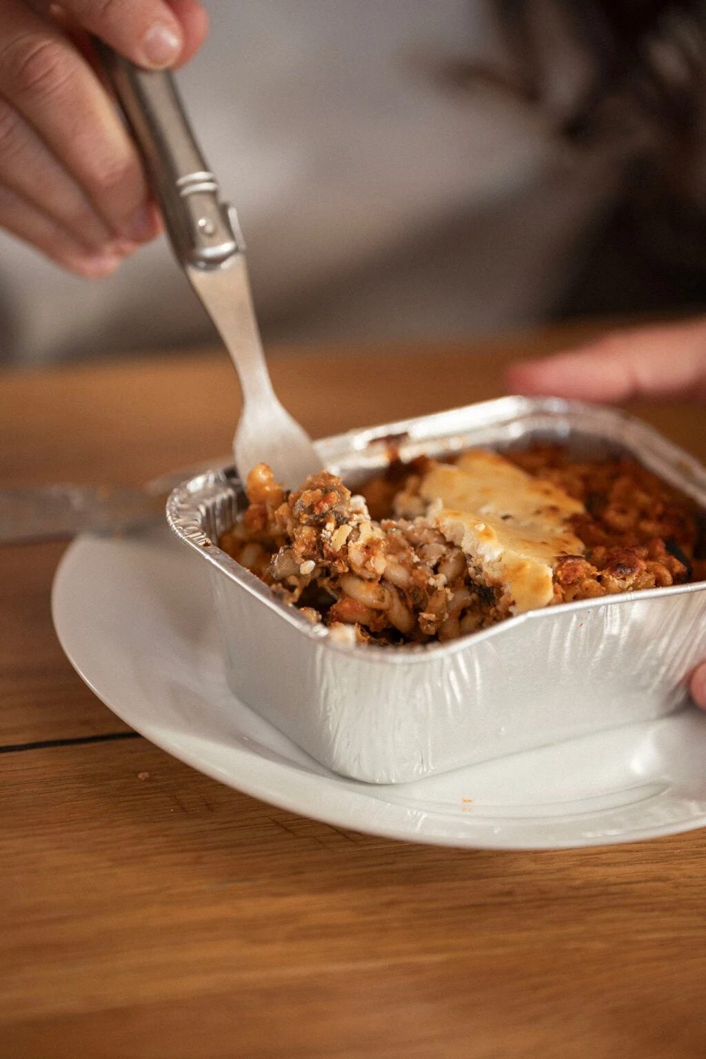 Une personne plante sa fourchette dans un gratin La Brigade de Véro servi dans son assiette